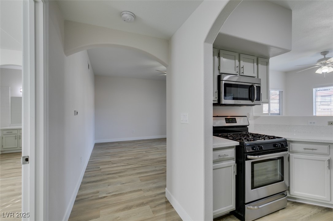 5525 West Flamingo Road, Unit 1028 Las Vegas, NV 89103 - Photo 6 of 42 Kitchen with arched walkways, stainless steel appliances, a ceiling fan, light wood finished floors, and white cabinetry