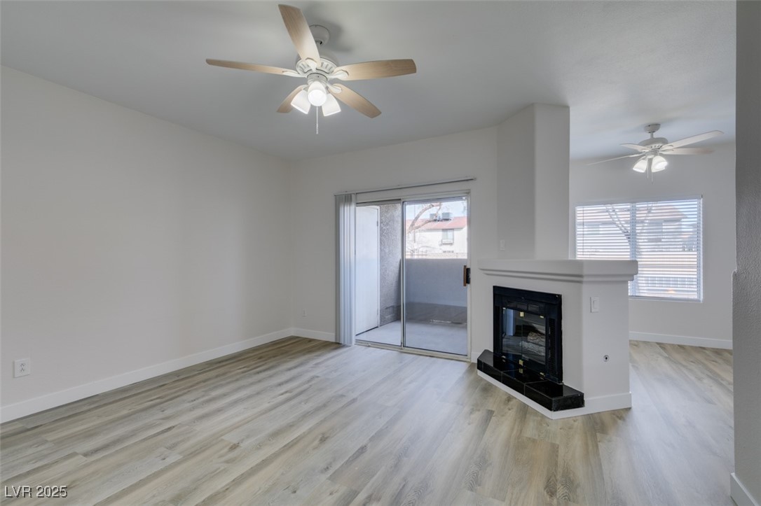 5525 West Flamingo Road, Unit 1028 Las Vegas, NV 89103 - Photo 8 of 42 Unfurnished living room featuring light wood finished floors, ceiling fan, and a tiled fireplace