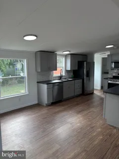 a kitchen with stainless steel appliances wooden floor and a refrigerator
