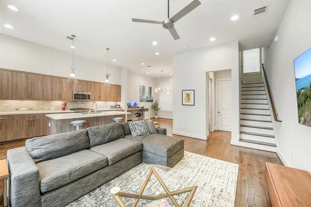 a living room with stainless steel appliances furniture and wooden floor