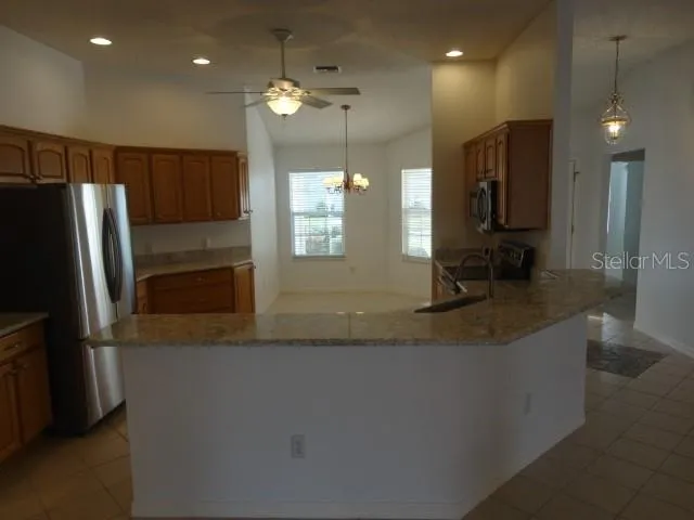 a kitchen with stainless steel appliances granite countertop a sink a stove and a refrigerator