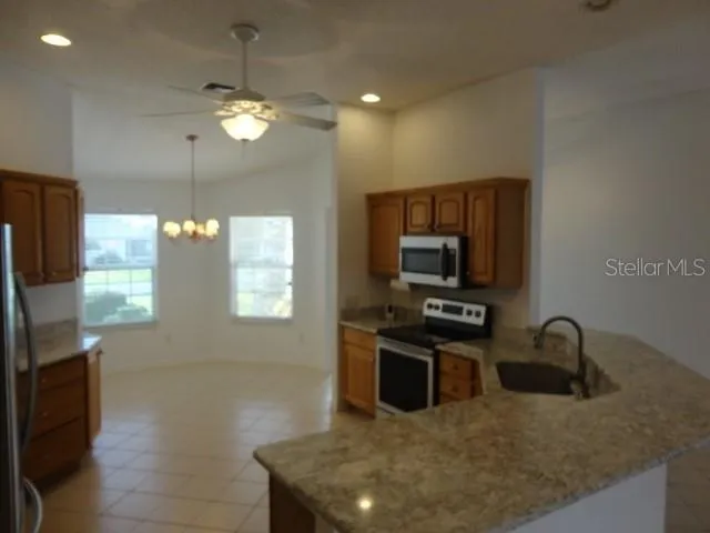 a kitchen with stainless steel appliances granite countertop a refrigerator a sink and a stove