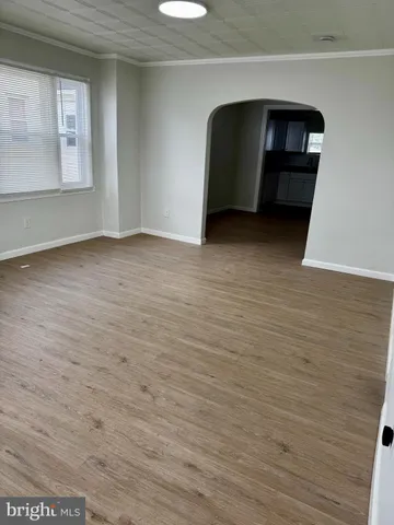 a view of kitchen and empty room with wooden floor
