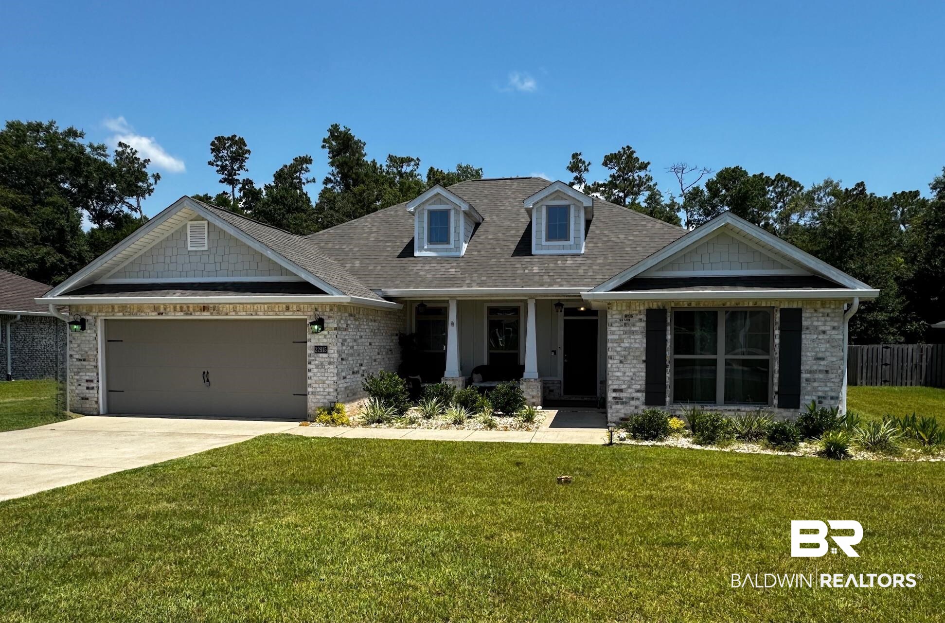 32915 Arbor Ridge Circle Lillian, AL 36549 - Photo 1 of 26 View of front of property featuring brick siding, an attached garage, a front yard, concrete driveway, and covered porch
