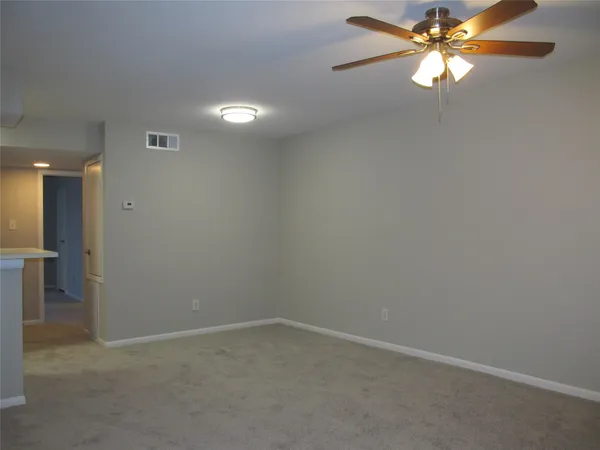 a view of an empty room with a ceiling fan and window