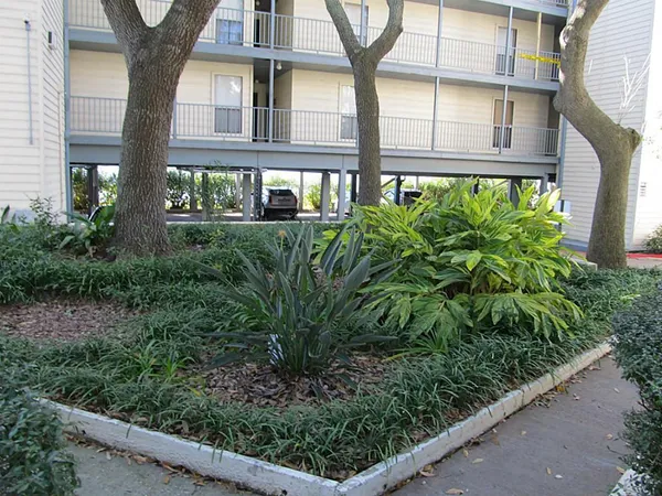 a flower garden is sitting in front of a brick house