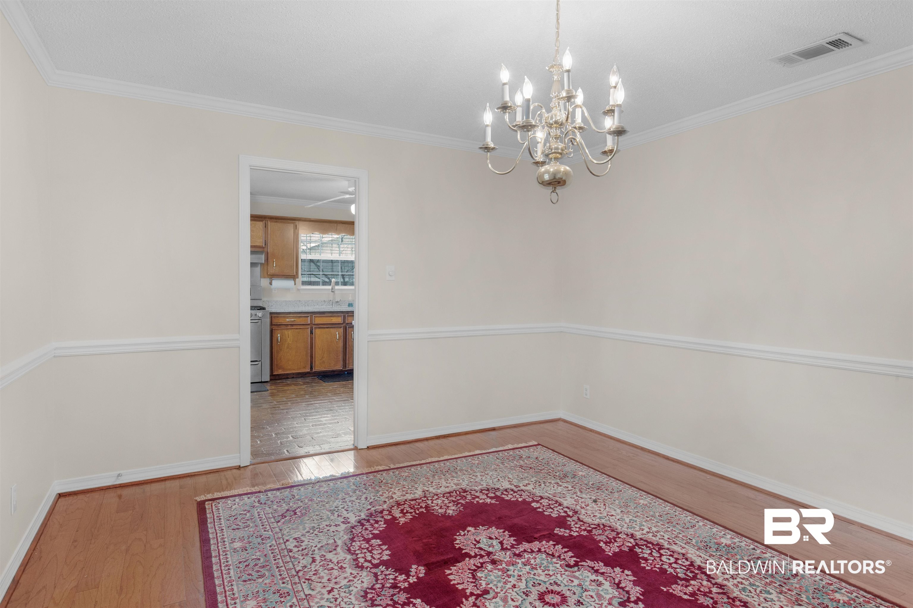 7225 Smithfield Road East Mobile, AL 36695 - Photo 3 of 27 Dining space with visible vents, baseboards, a chandelier, ornamental molding, and wood finished floors
