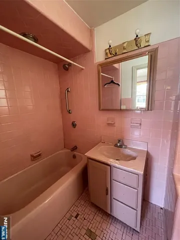 a bathroom with a tub sink and mirror
