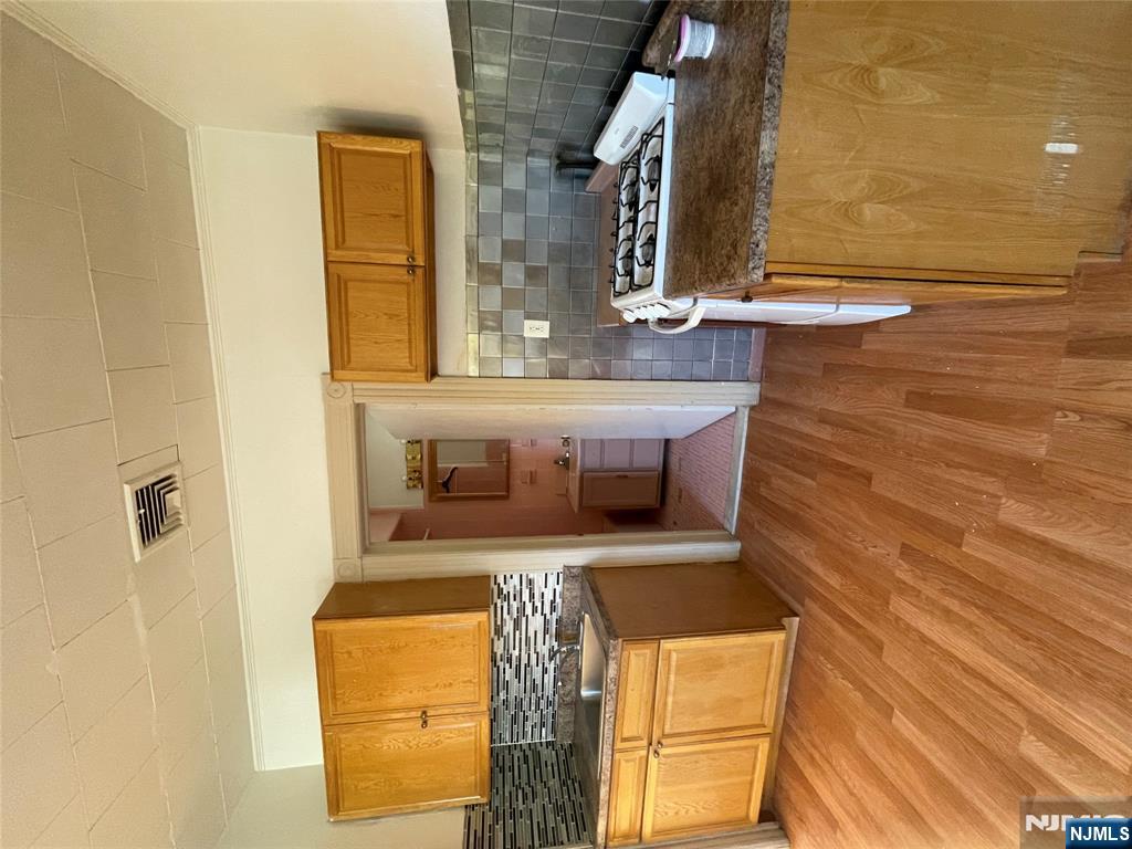 71 Passaic Street, Unit 2 Passaic, NJ 07055 - Photo 4 of 11 a kitchen with granite countertop a stove and a wooden floors