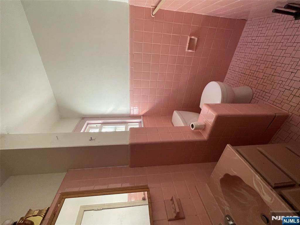 71 Passaic Street, Unit 2 Passaic, NJ 07055 - Photo 10 of 11 a bathroom with a sink and mirror with toilet