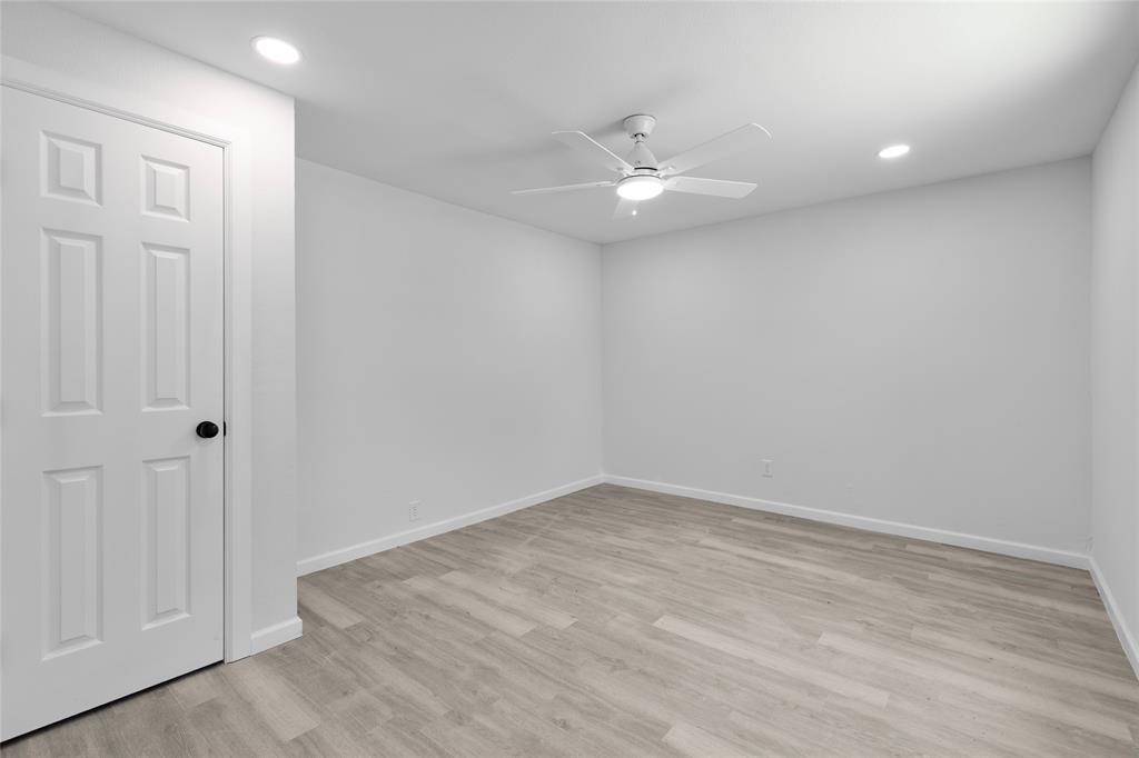 211 Southeast 7th Street Cooper, TX 75432 - Photo 13 of 29 an empty room with a ceiling fan and wooden floor