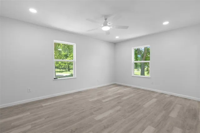 an empty room with wooden floor and windows