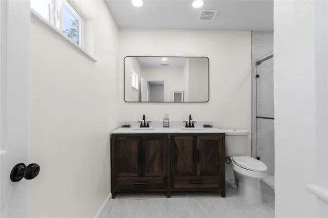 a bathroom with a toilet sink vanity and mirror
