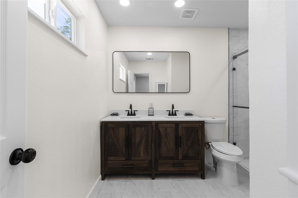 211 Southeast 7th Street Cooper, TX 75432 - Photo 21 of 29 a bathroom with a toilet sink vanity and mirror
