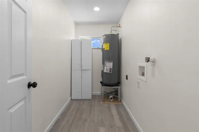 a view of a hallway with wooden floor a sink and a mirror