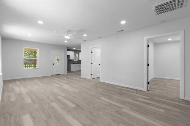 an empty room with wooden floor and a hallway