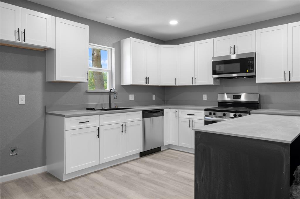 211 Southeast 7th Street Cooper, TX 75432 - Photo 8 of 29 a kitchen with stainless steel appliances granite countertop a sink a stove top oven a counter space and cabinets