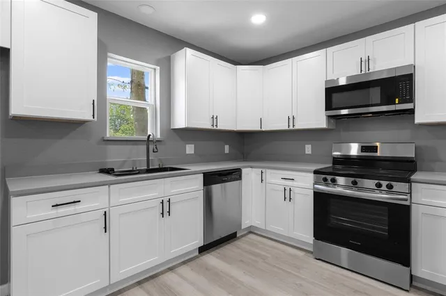 a kitchen with stainless steel appliances granite countertop a sink a stove and microwave
