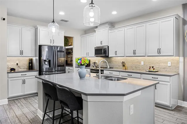 a kitchen with stainless steel appliances granite countertop a stove refrigerator a sink dishwasher a dining table and chairs with wooden floor