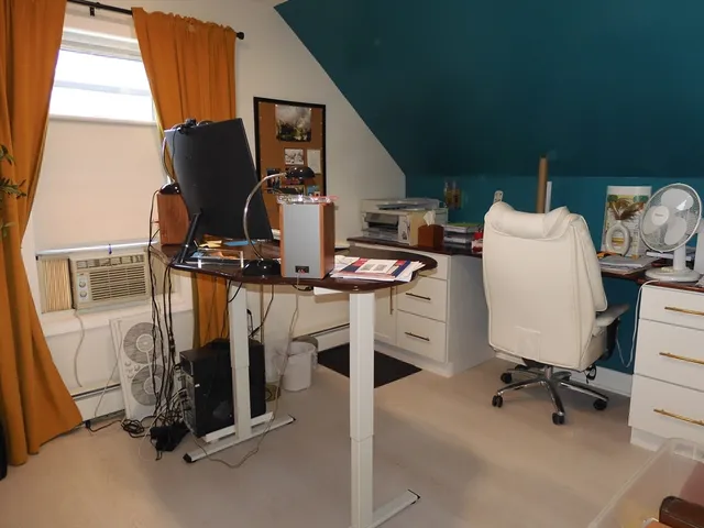 a view of a workspace with furniture and a window