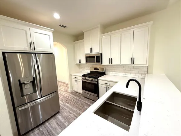 a kitchen with granite countertop a refrigerator and a stove top oven