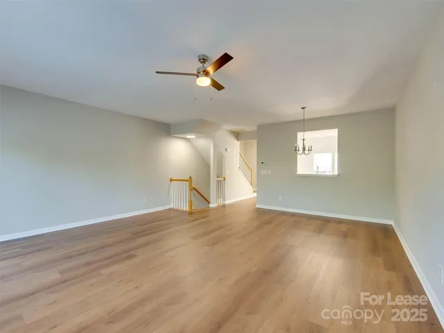 a view of an empty room with wooden floor and windows