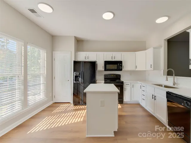 a kitchen with stainless steel appliances a sink a stove a refrigerator cabinets and a window