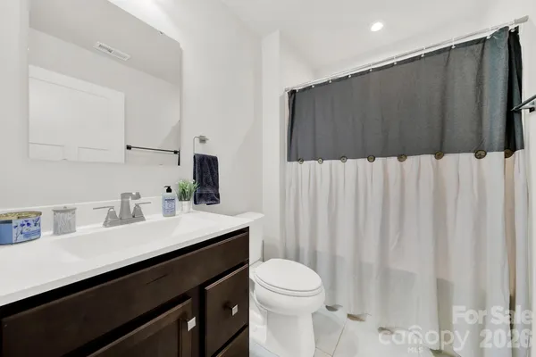 a bathroom with a sink a toilet a mirror and shower curtain