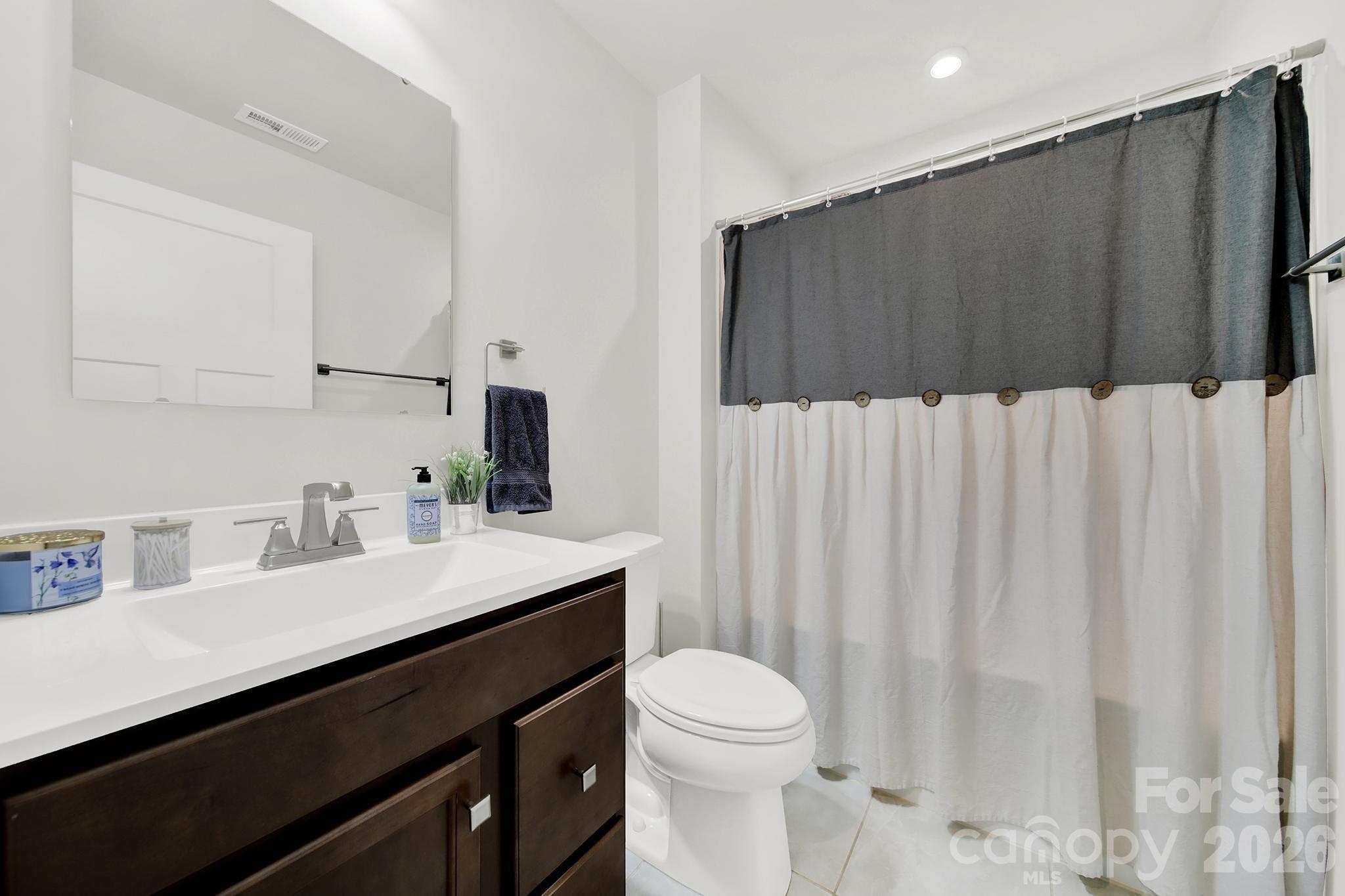 515 Grandiflora Avenue Lancaster, SC 29720 - Photo 17 of 29 a bathroom with a sink a toilet a mirror and shower curtain