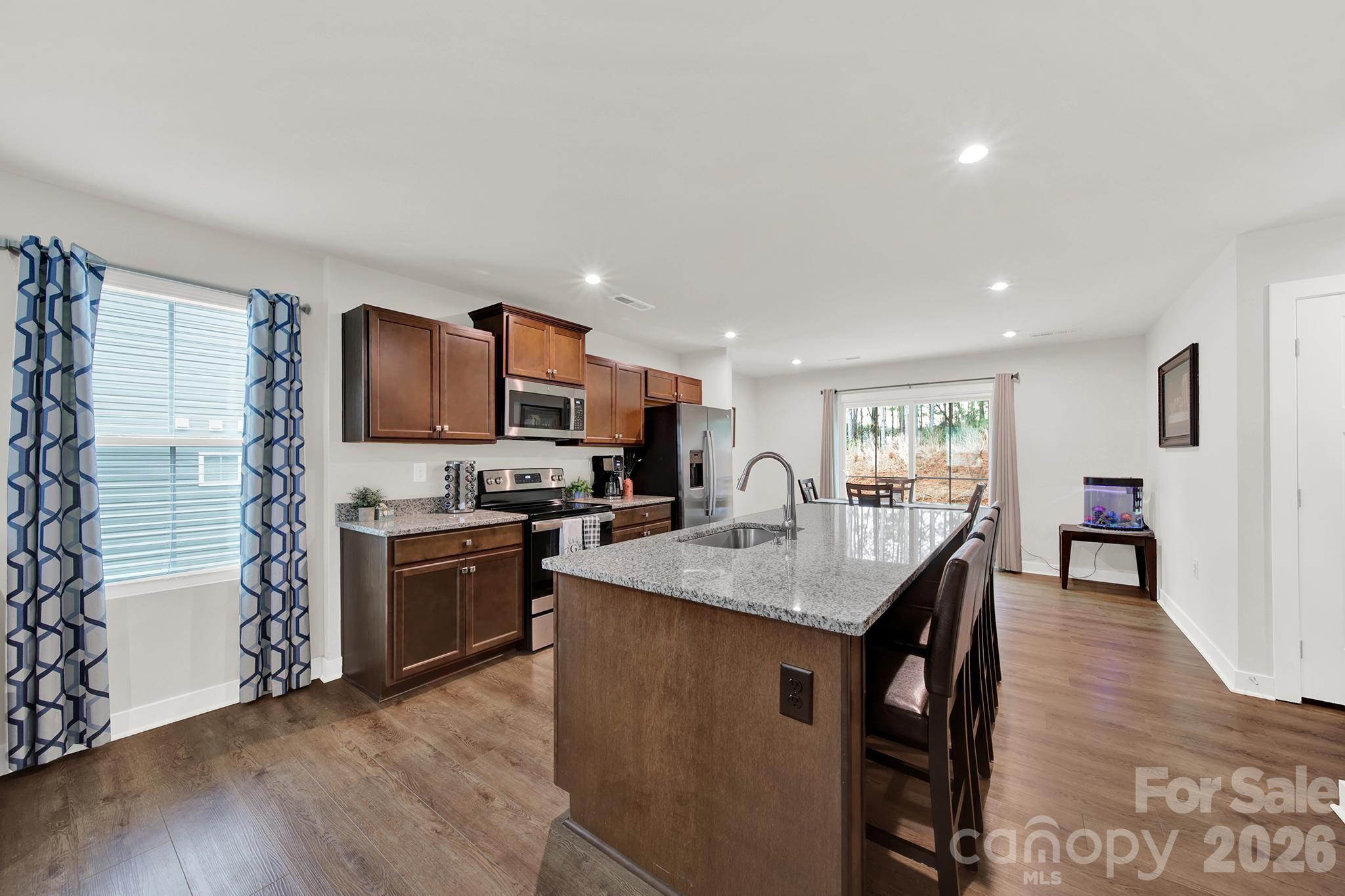 515 Grandiflora Avenue Lancaster, SC 29720 - Photo 8 of 29 a kitchen with stainless steel appliances granite countertop a stove top oven a sink dishwasher a dining table and chairs with wooden floor