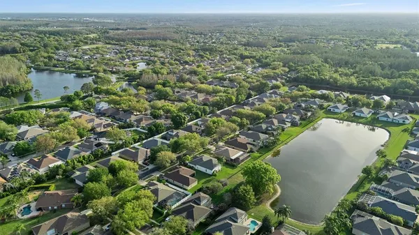 an aerial view of a residential houses with outdoor space and trees