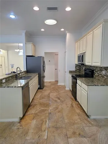 a large kitchen with kitchen island granite countertop a stove top oven a sink a counter space and cabinets