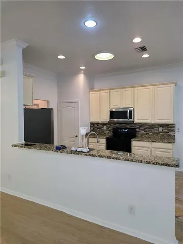 a kitchen with granite countertop a refrigerator and a stove top oven