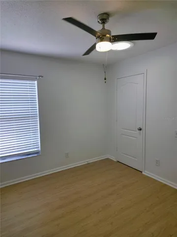 an empty room with a chandelier fan and windows
