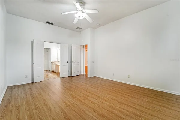 an empty room with wooden floor and ceiling fan