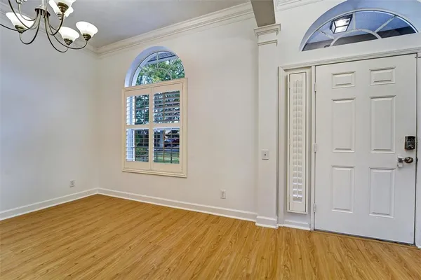 an empty room with wooden floor cabinet and windows