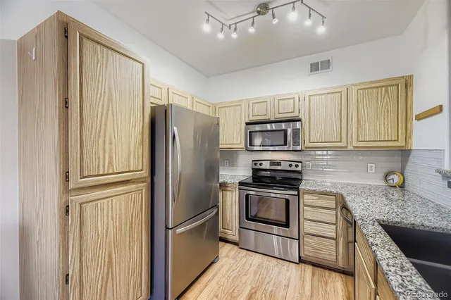a kitchen with stainless steel appliances granite countertop a refrigerator microwave and stove