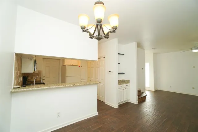 a view of a hallway with wooden floor and chandelier