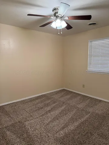 an empty room with a chandelier fan and windows
