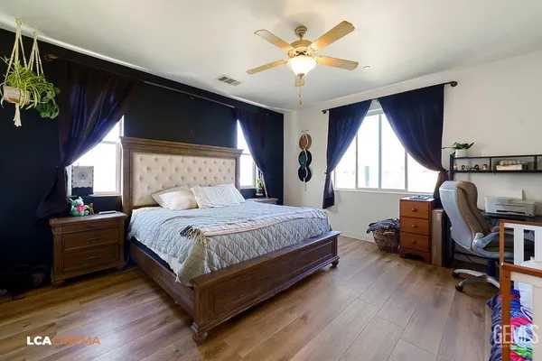 a bedroom with a bed a desk and chair with wooden floor