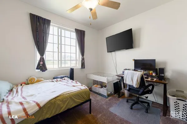 a bedroom with a bed tv and a window