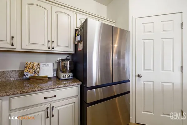 a kitchen with granite countertop a refrigerator and cabinets