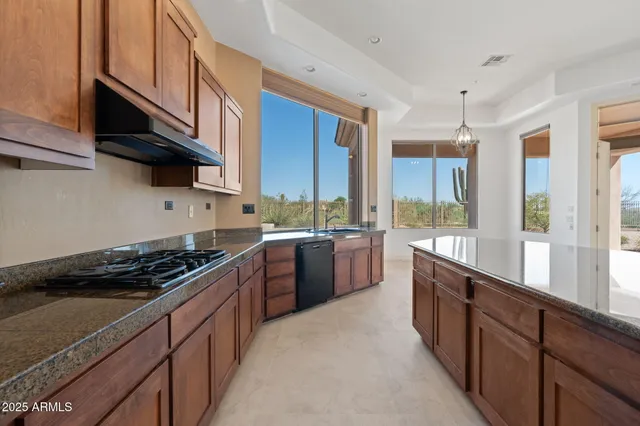 a kitchen with granite countertop a refrigerator and a stove top oven