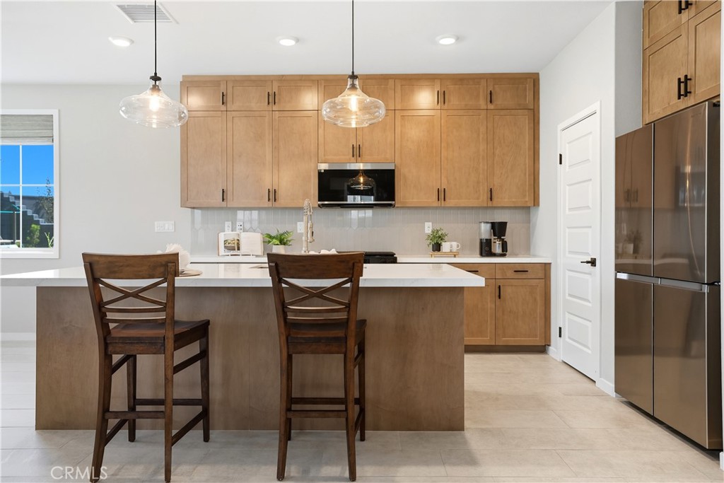 1341 Roots Way Rancho Mission Viejo, CA 92694 - Photo 14 of 75 a kitchen with a refrigerator a stove a sink and a dining table with white cabinets