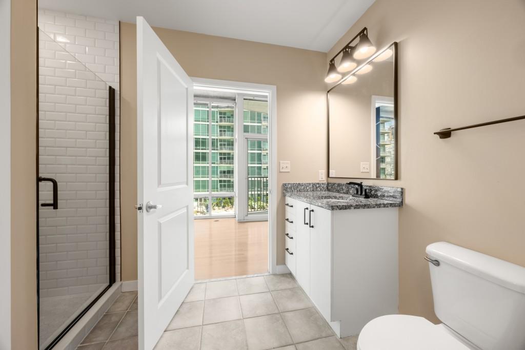 923 Peachtree Street Northeast, Unit 932 Atlanta, GA 30309 - Photo 19 of 69 a bathroom with a granite countertop sink toilet and shower