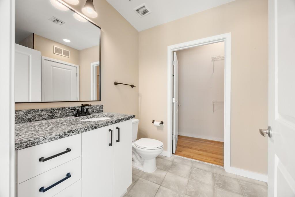 923 Peachtree Street Northeast, Unit 932 Atlanta, GA 30309 - Photo 21 of 69 a bathroom with a granite countertop sink a toilet and a mirror