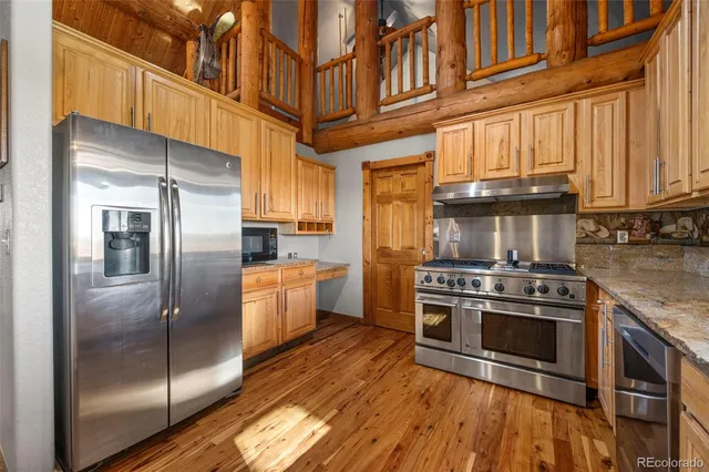 a kitchen with stainless steel appliances granite countertop a refrigerator a stove and a sink