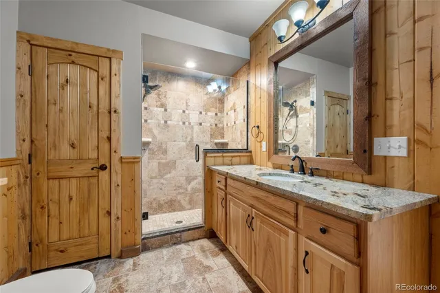 a bathroom with a granite countertop sink a mirror and a shower