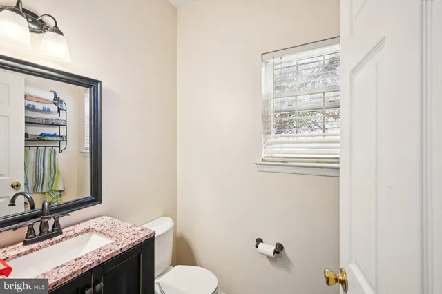 a bathroom with a granite countertop sink toilet and mirror