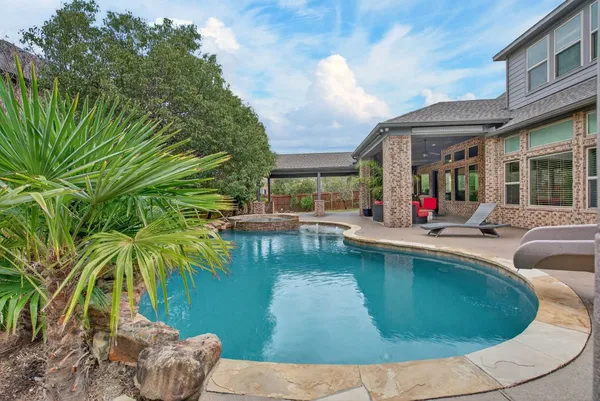 a view of a house with pool plants and large trees